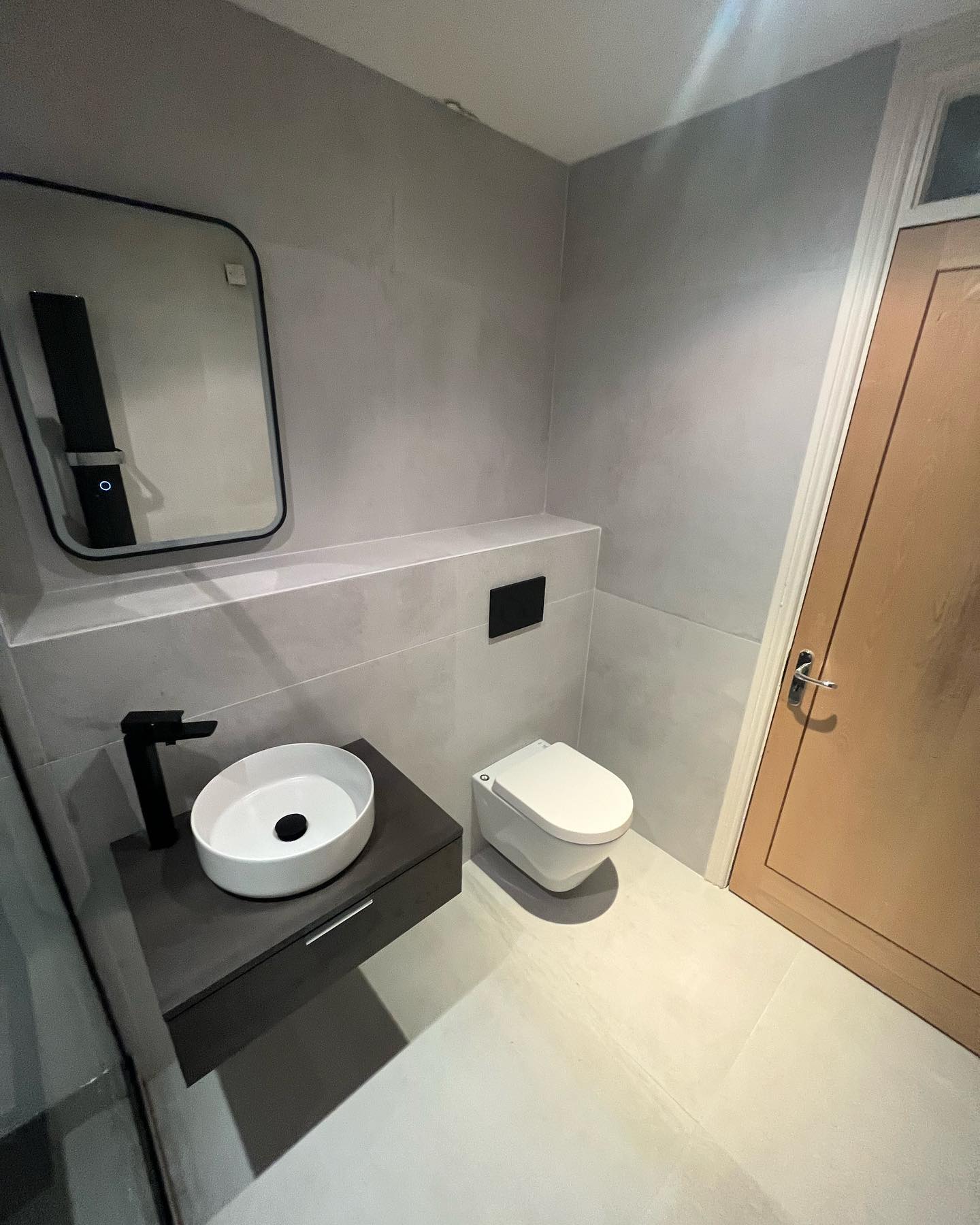 Grey wetroom vanity with countertop basin, black tap and wall-mounted mirror