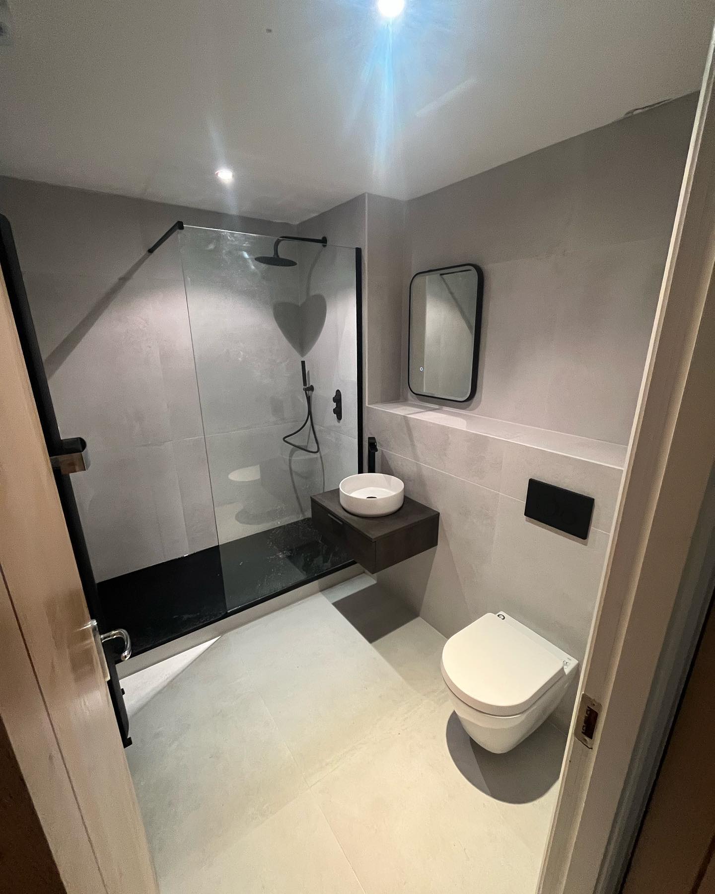 Grey wetroom with rainfall shower, wall-hung vanity and black fittings
