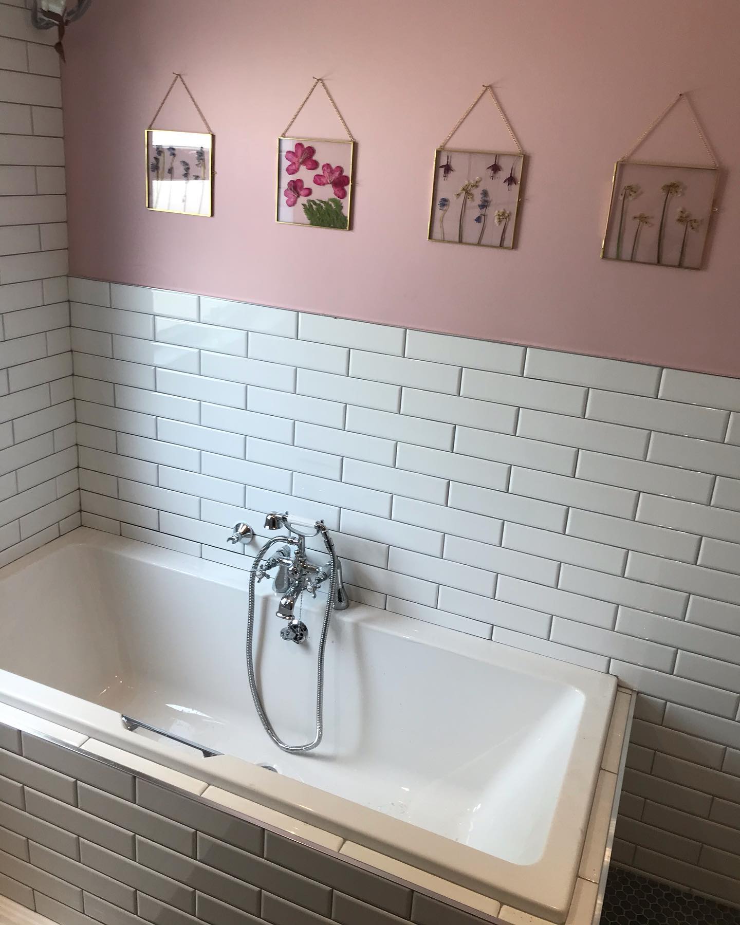 White bath with tiled surround and pink painted wall