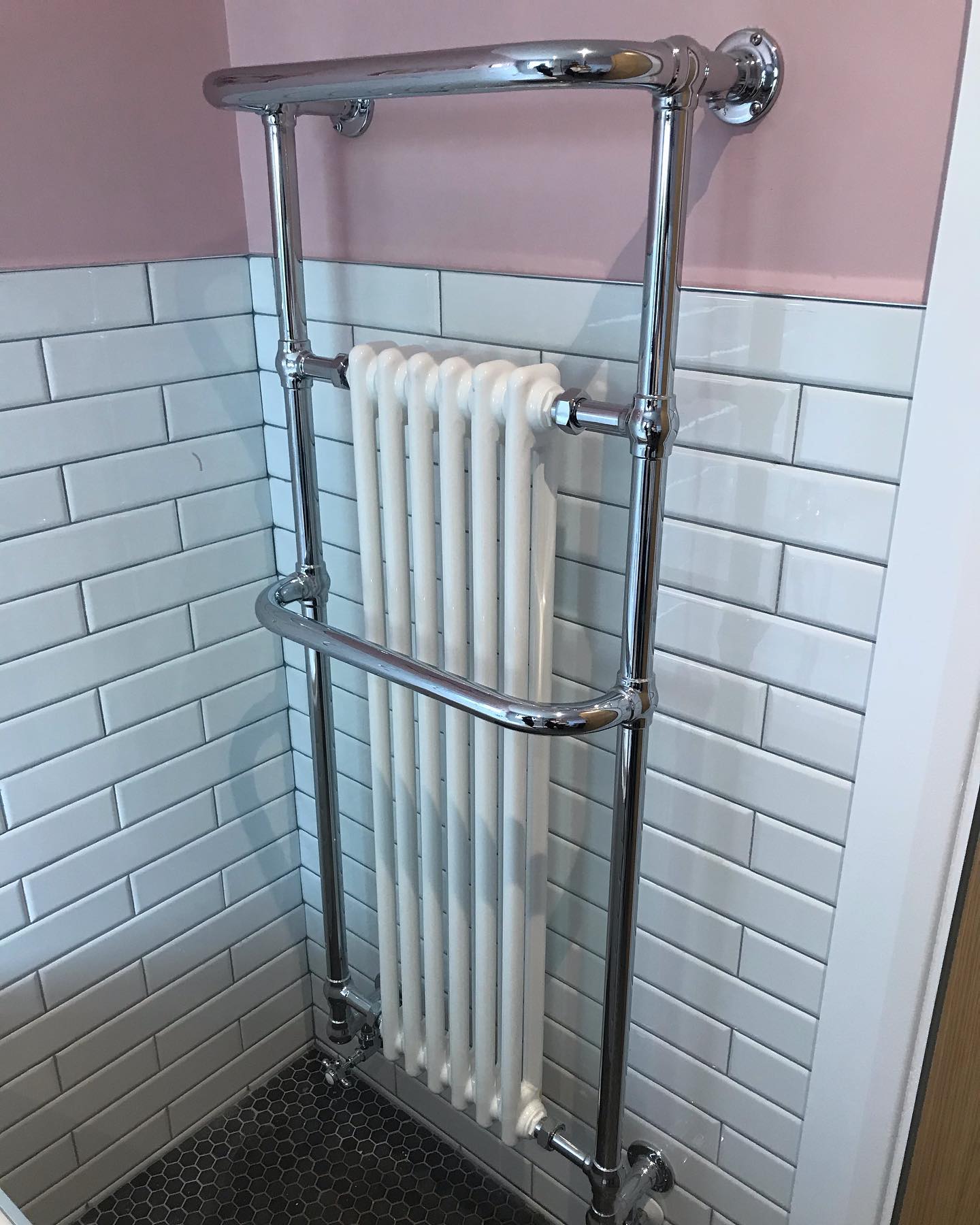 Chrome towel rail fitted over a white bathroom radiator