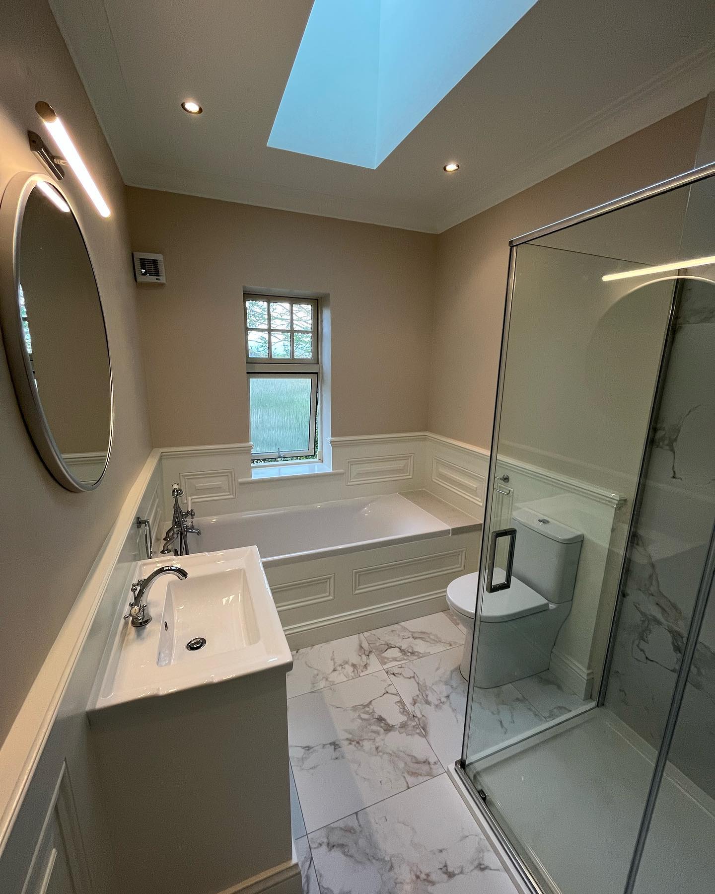 Bathroom with skylight, panelled bath surround and glass shower enclosure